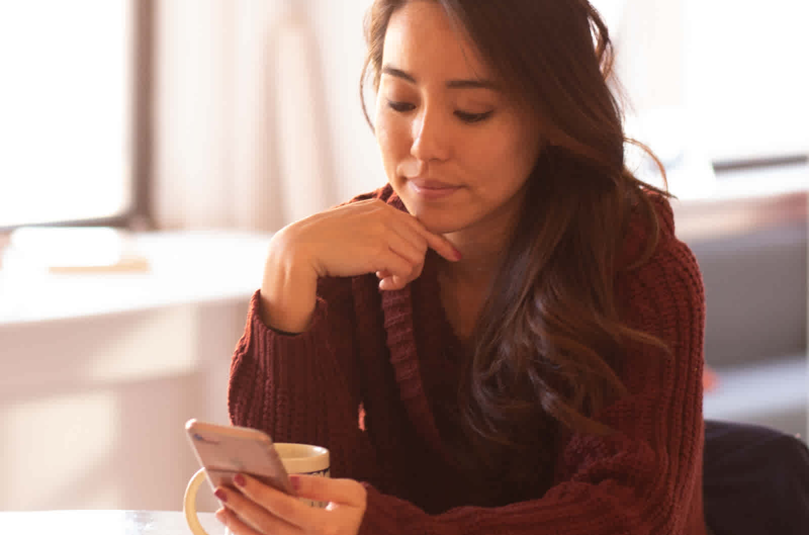 Woman in a dark sweater holds a smartphone