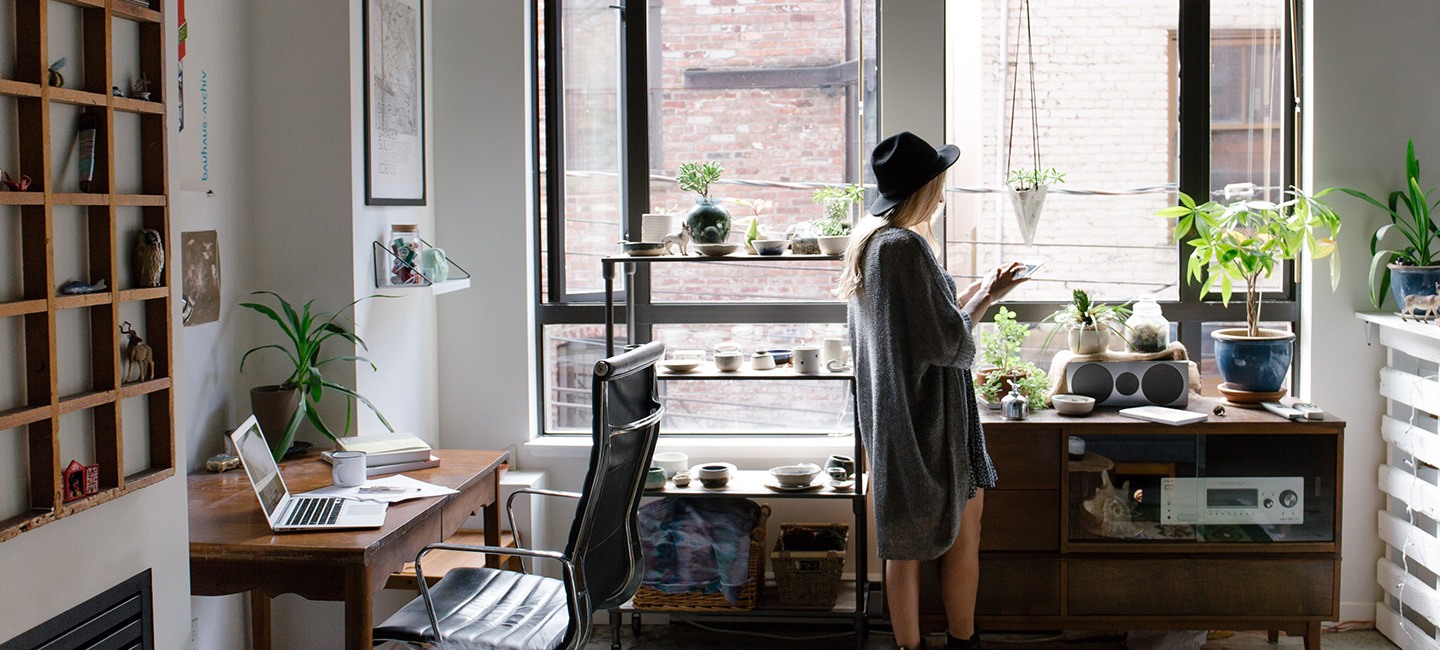 Woman in apartment looking at smartphone | Root renters insurance main page