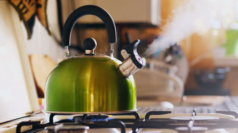 Kettle boiling on a gas stove. Boiling green kettle boiling with steam emitted from spout.