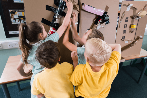 pupils in a classroom testing a marble run made out of cardboard