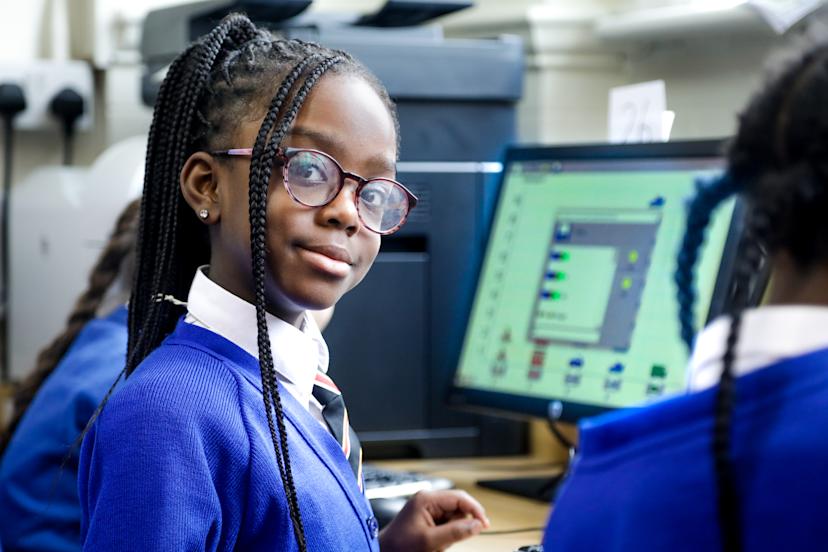 Black female primary-school pupil in uniform turns away from the ...