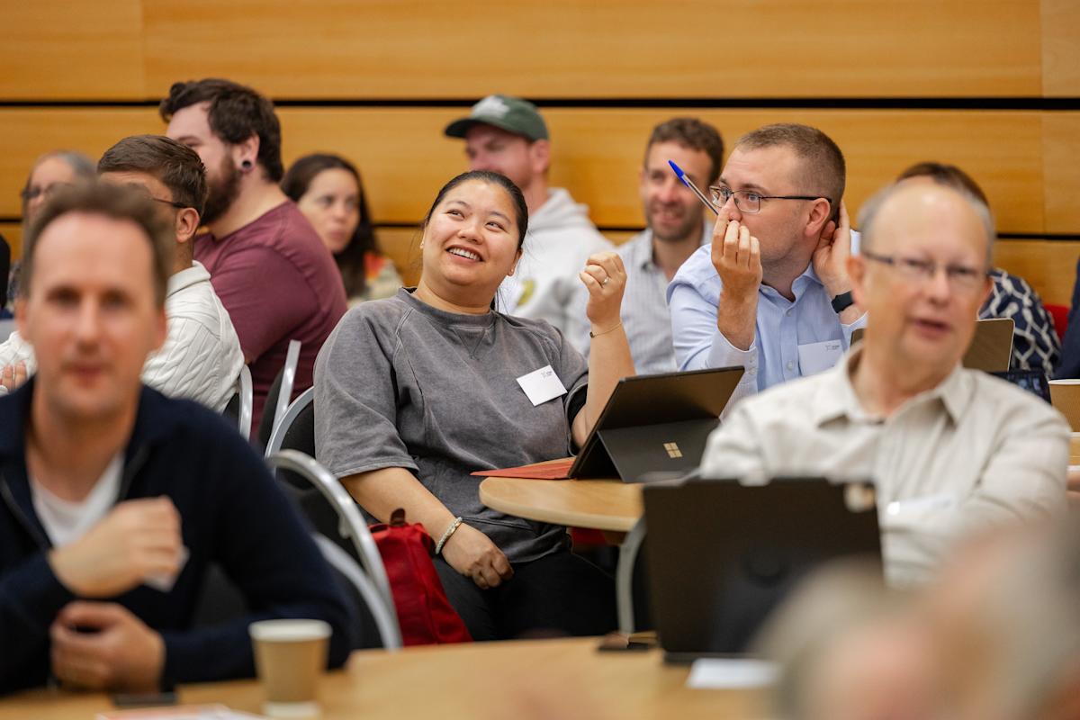 A group of educators sat during a keynote lecture, smiling and chatting