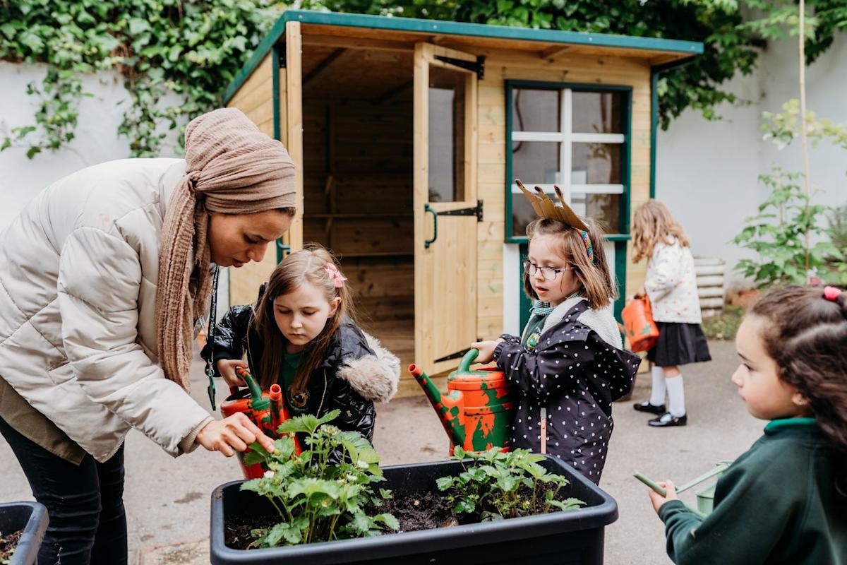Children and their teacher watering plants