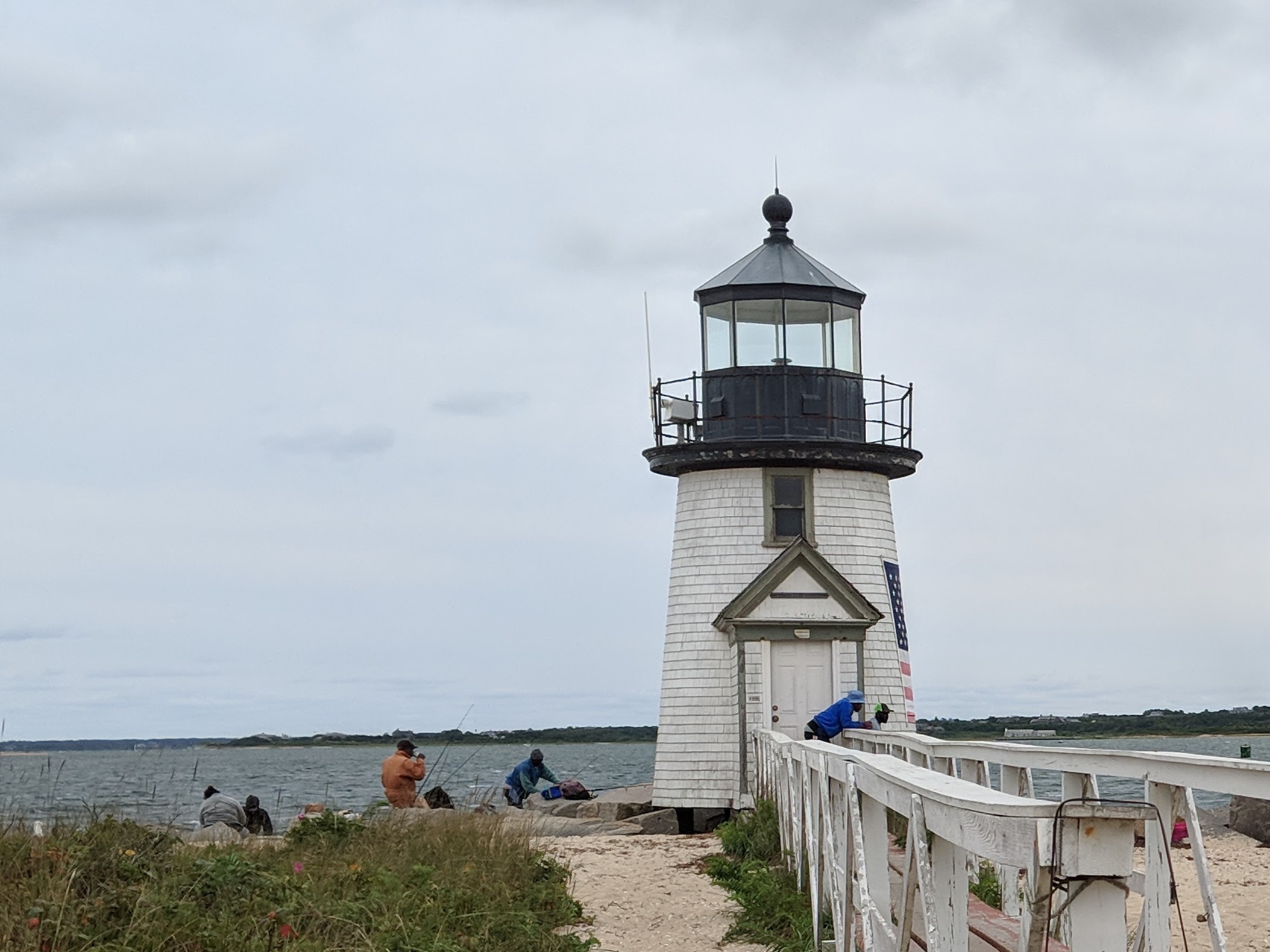 Small historic lighthouse with fishermen working beside it