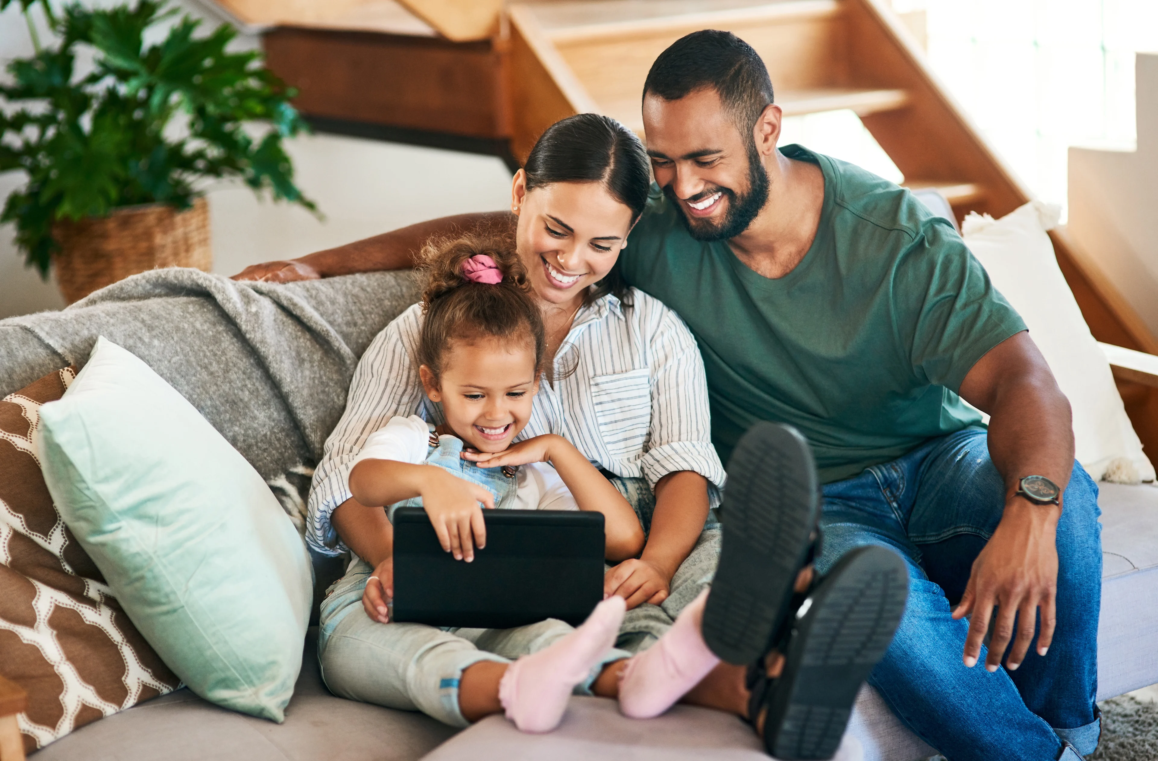 Young family on the couch looking at electronic device.