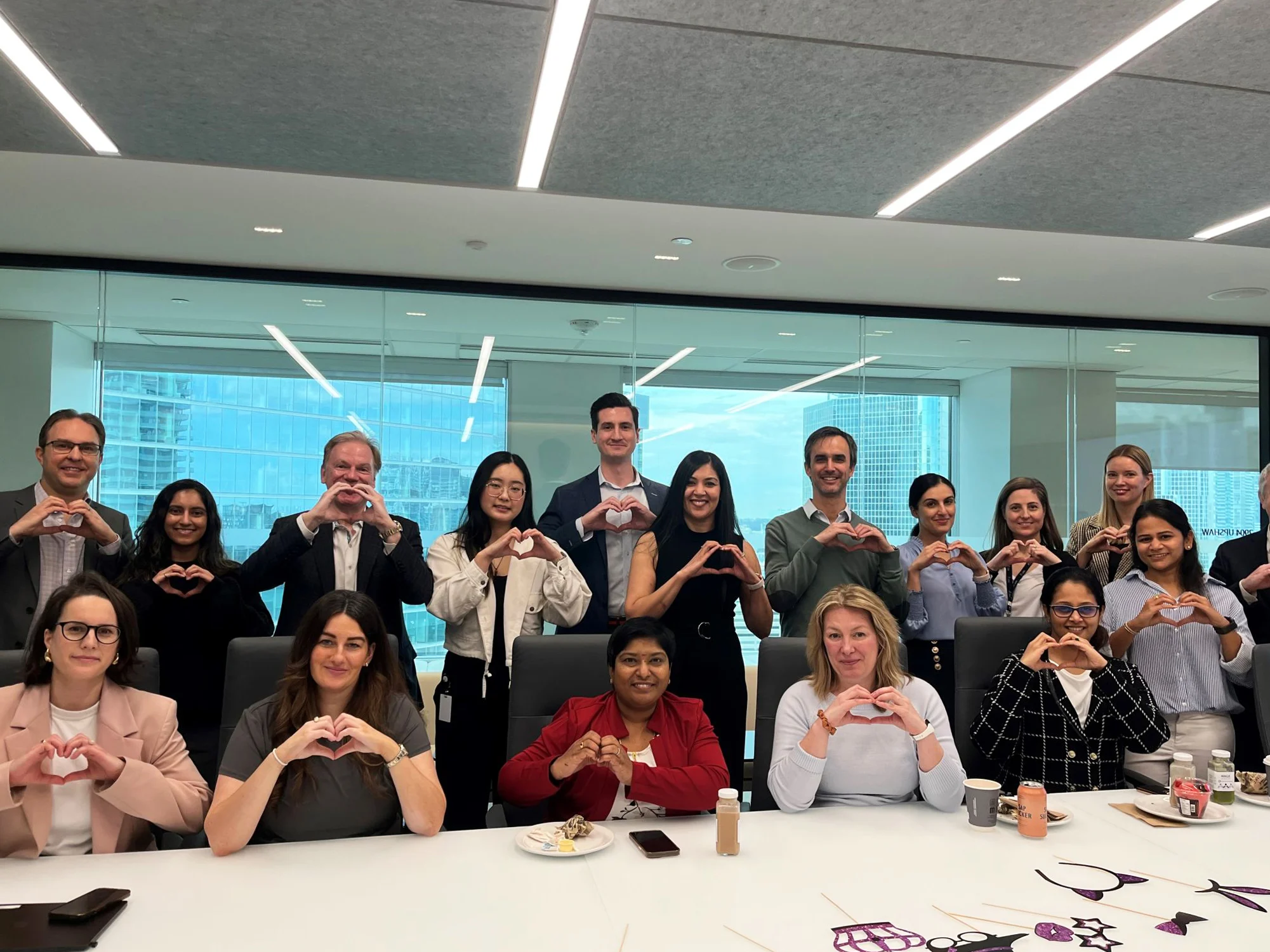 Team in the office making a heart shape with hands