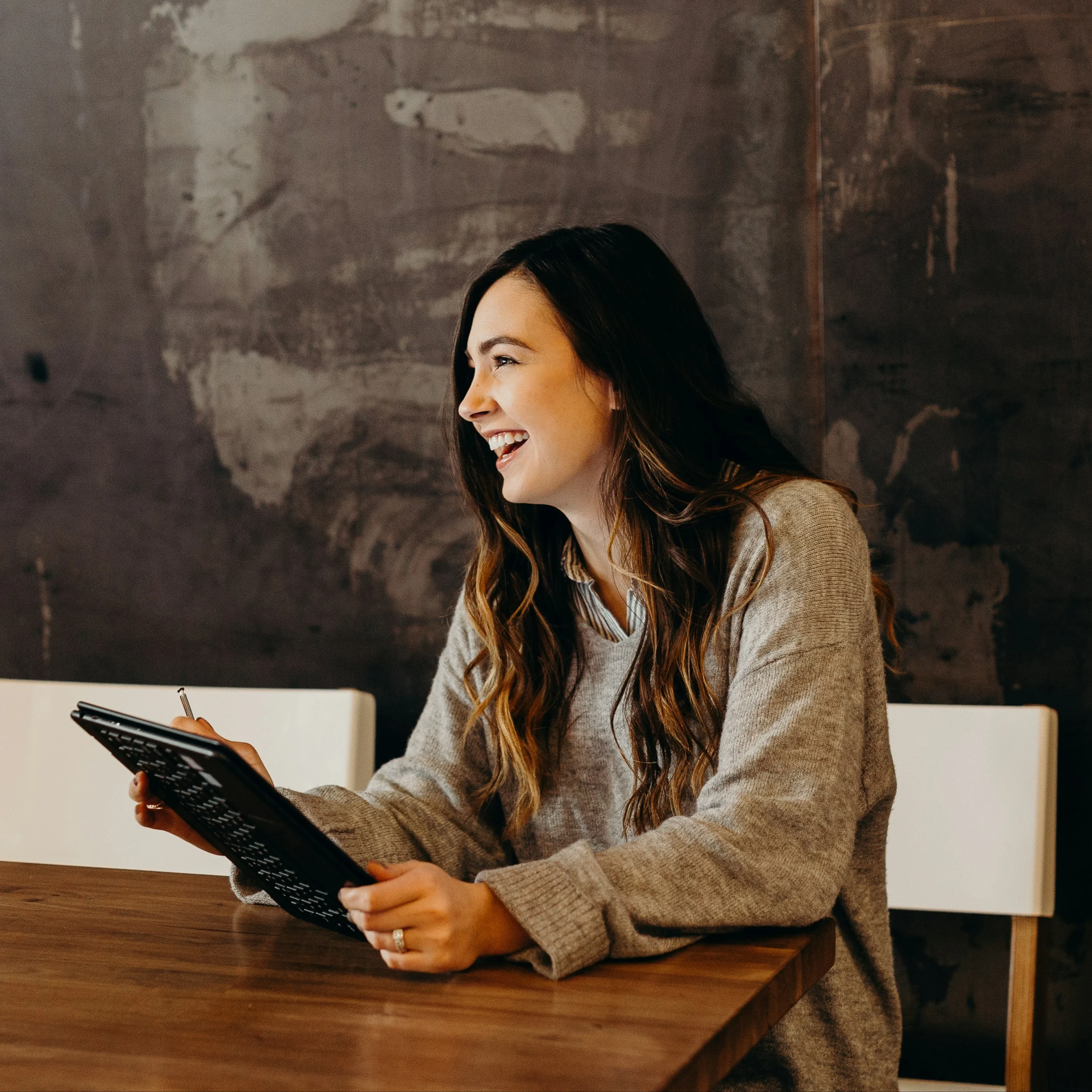 woman sitting around table holding tablet
