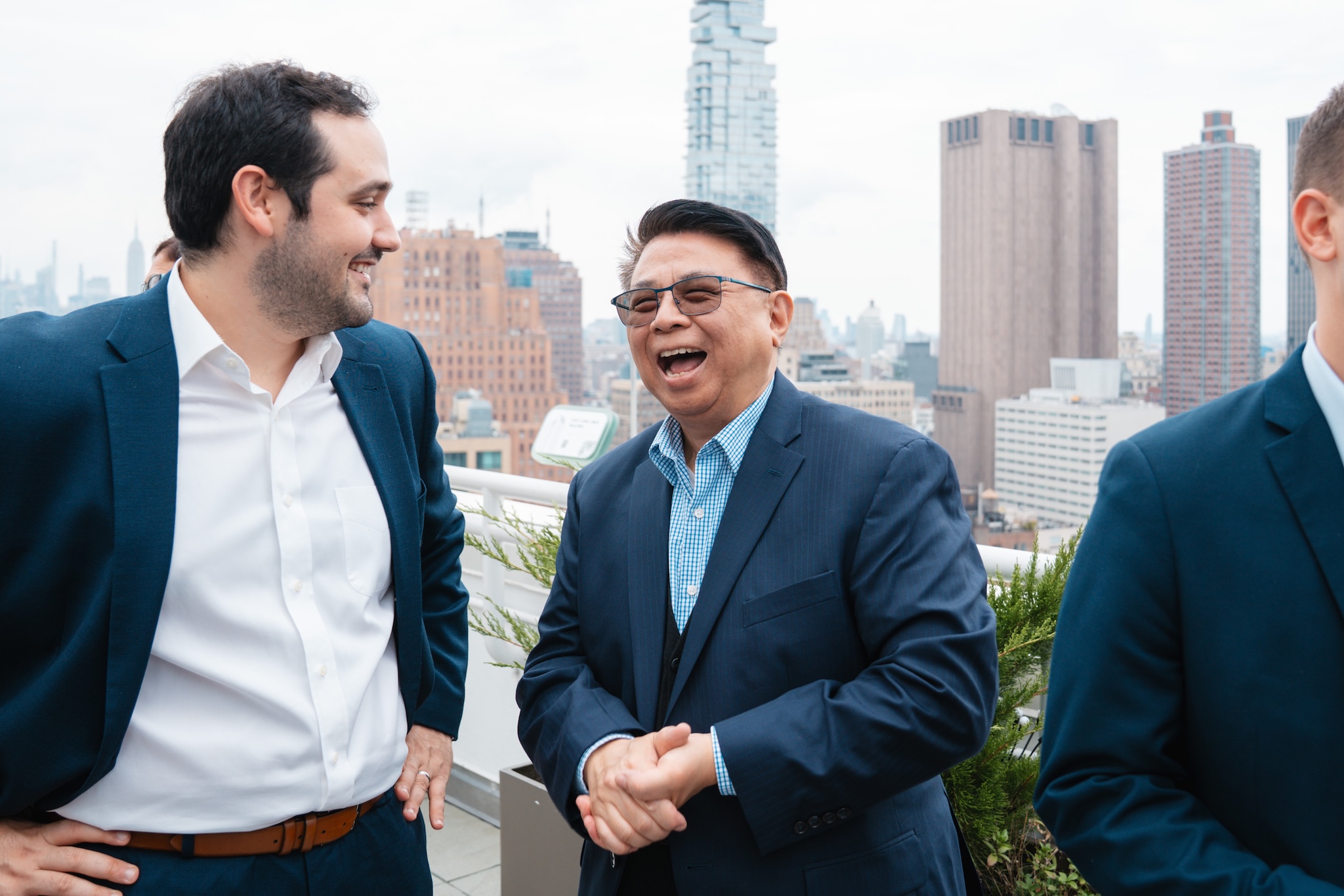 Laughing men in suits on a NYC rooftop