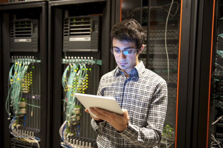 A software engineer stands in front of servers.