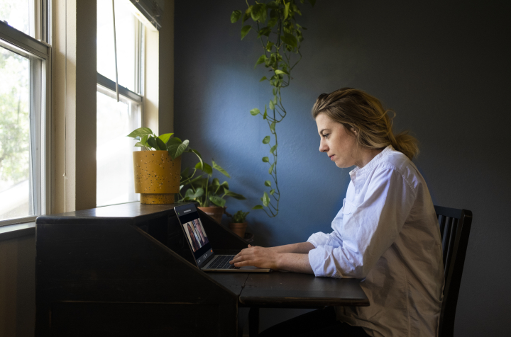 Side view of a person working from home typing on their laptop while on a video call.