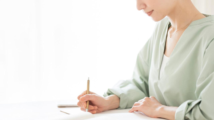 何かを書き込む女性の手元の画像