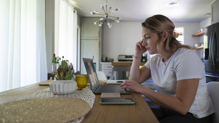 Side view of a person working from home and participating in a video meeting.