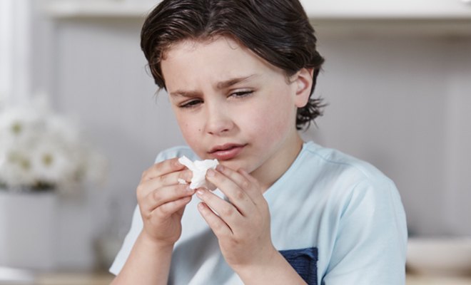 Boy wiping his sore nose with Puffs Plus Lotion