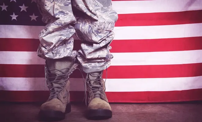 Person standing in military boots in front of the American flag