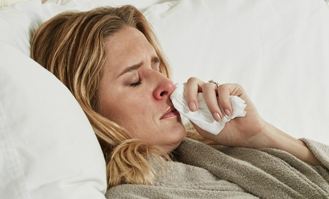 Woman under the weather blowing her nose with Puffs Plus Lotion