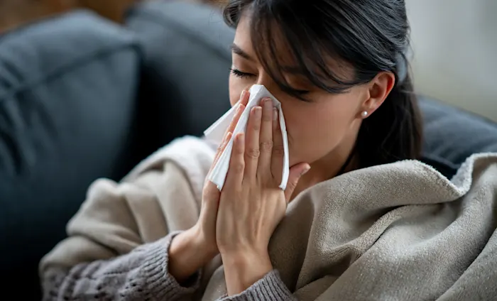 Woman blowing her nose on a couch Woman blowing her nose on a couch