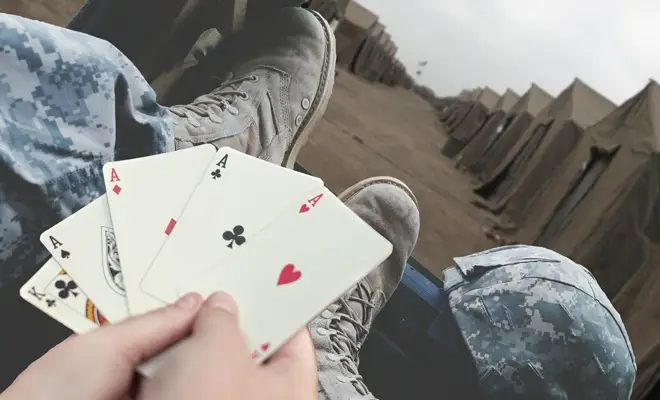 Military personnel holding playing cards with 4 different types of aces