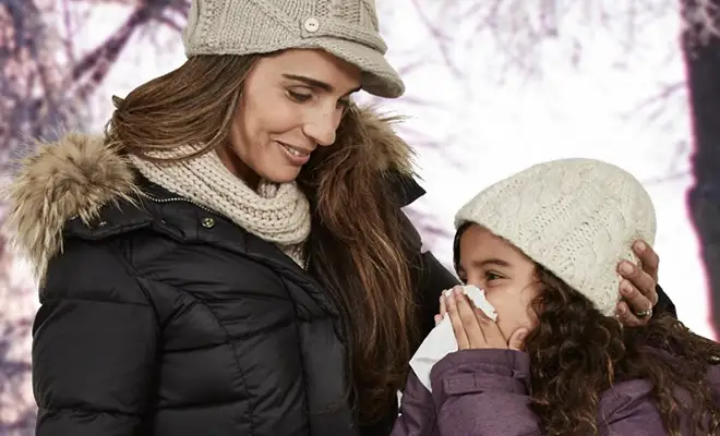 Mother comforts daughter while daughter blows her nose