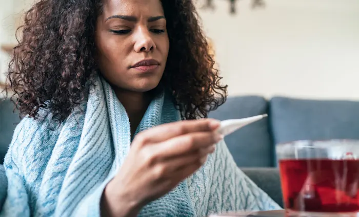 Sick woman checking thermometer to see if she has a fever