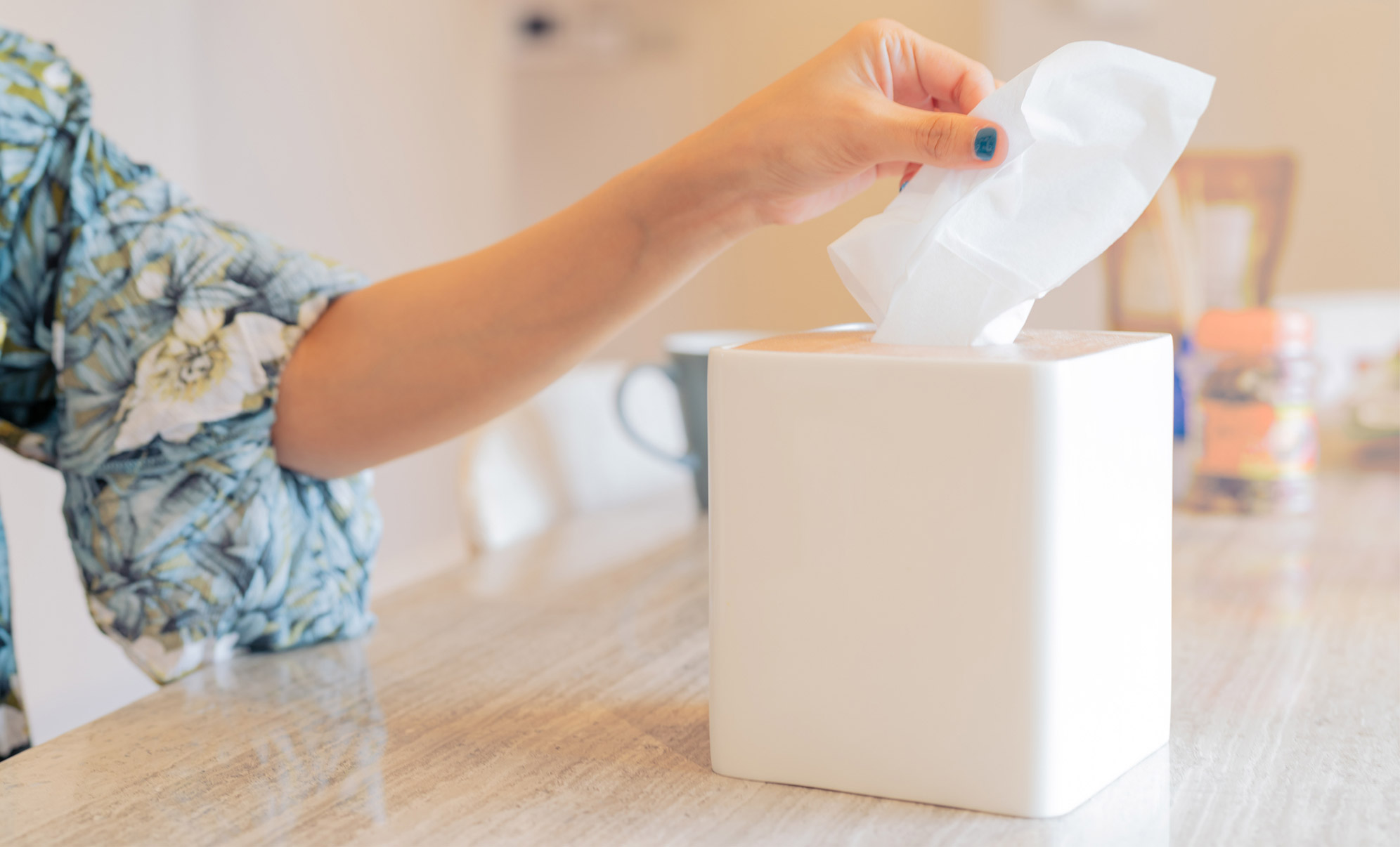 Woman wiping away tears in the kitchen with Puffs soft pack tissue