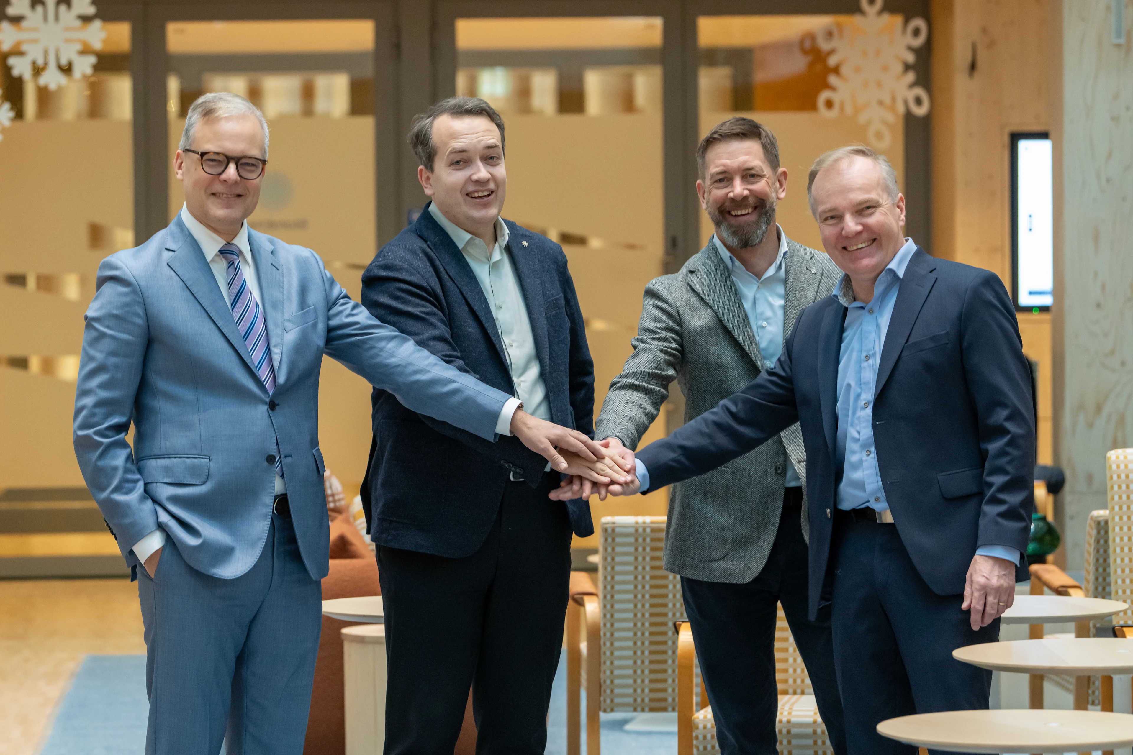 Yhteensä neljä Pihlajalinnan ja Stora Enson miestä seisoo sisätiloissa ja hymyilee kameralle kädet päällekkäin yhteistyön merkiksi.