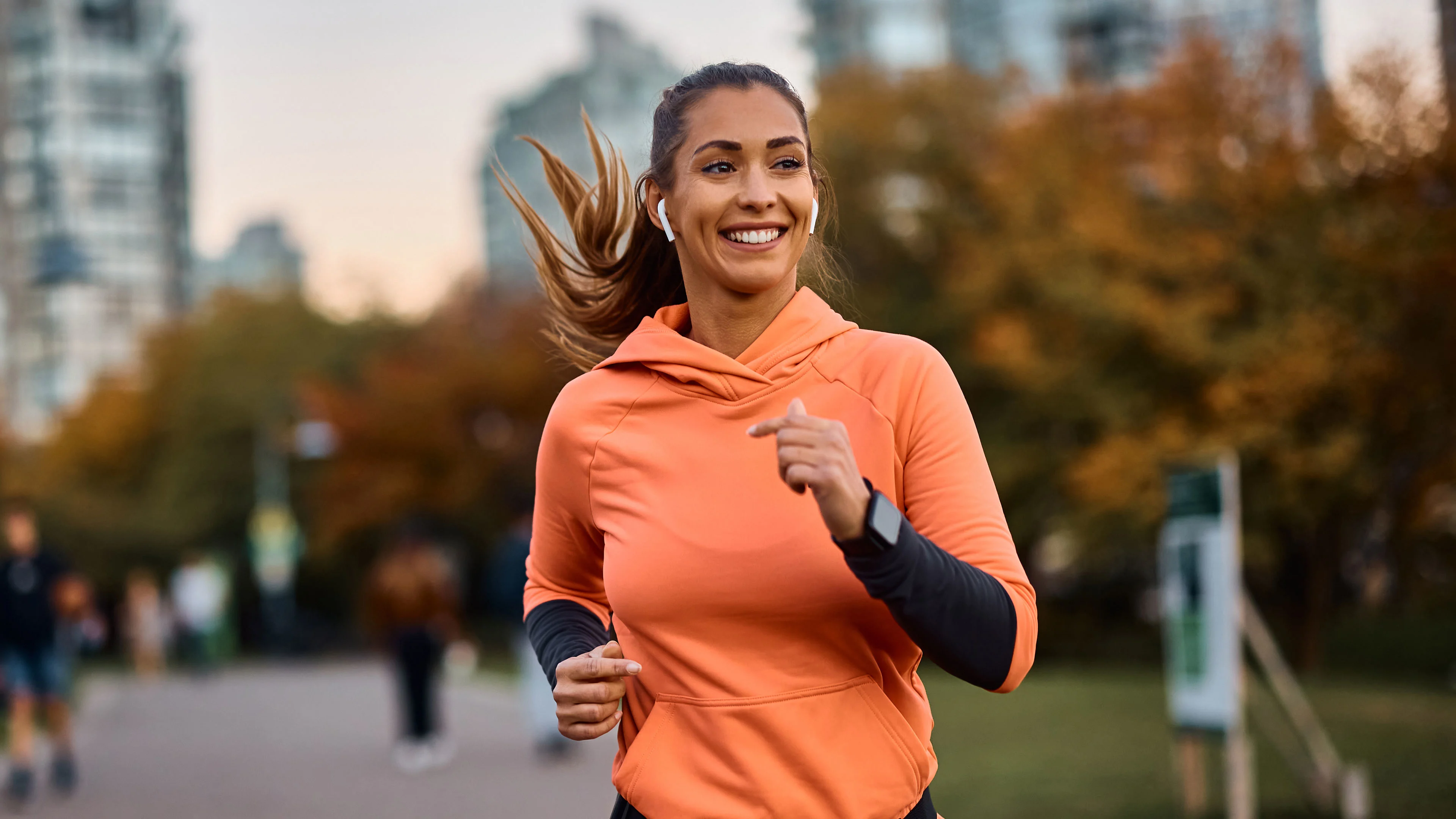 Oranssipaitainen nainen lenkkeilee puistossa.