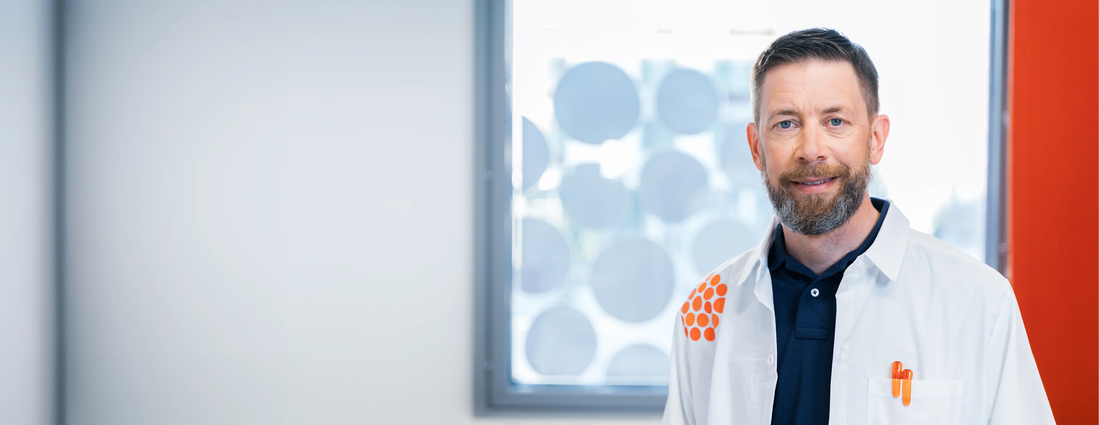 Lääkäri vastaanottohuoneessa katsoo kameraan