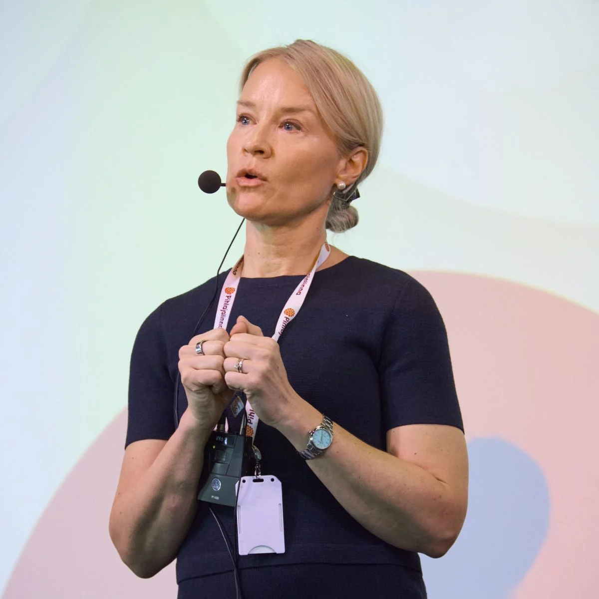 Vaaleahiuksinen asiantuntija puhumassa lavalla 