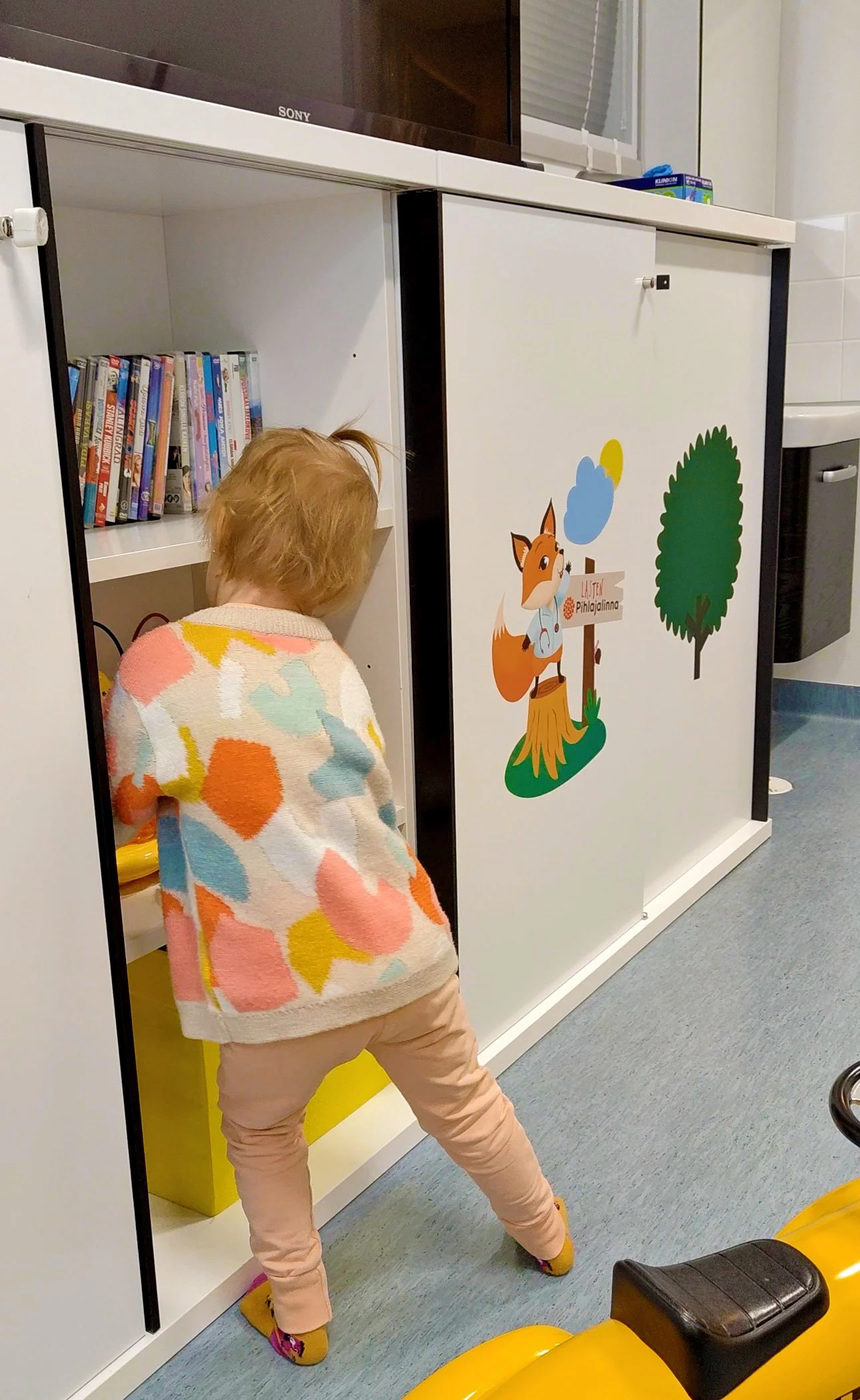Lapsi tutkii kirjahyllyä Pihlajalinnan tiloissa. 