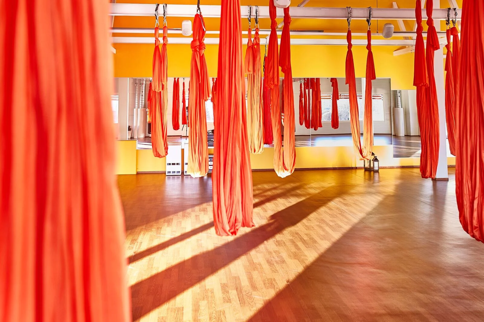 Sisätilakuva Pihlajalinna Järvenpäästä, jossa katosta roikkuu pilatekseen tarkoitettuja punaisia kankaita.