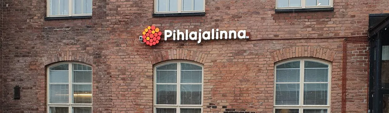 Näkymä Kelloportista ulkoa. Punaisen tiilitalon seinässä Pihlajalinnan logo.