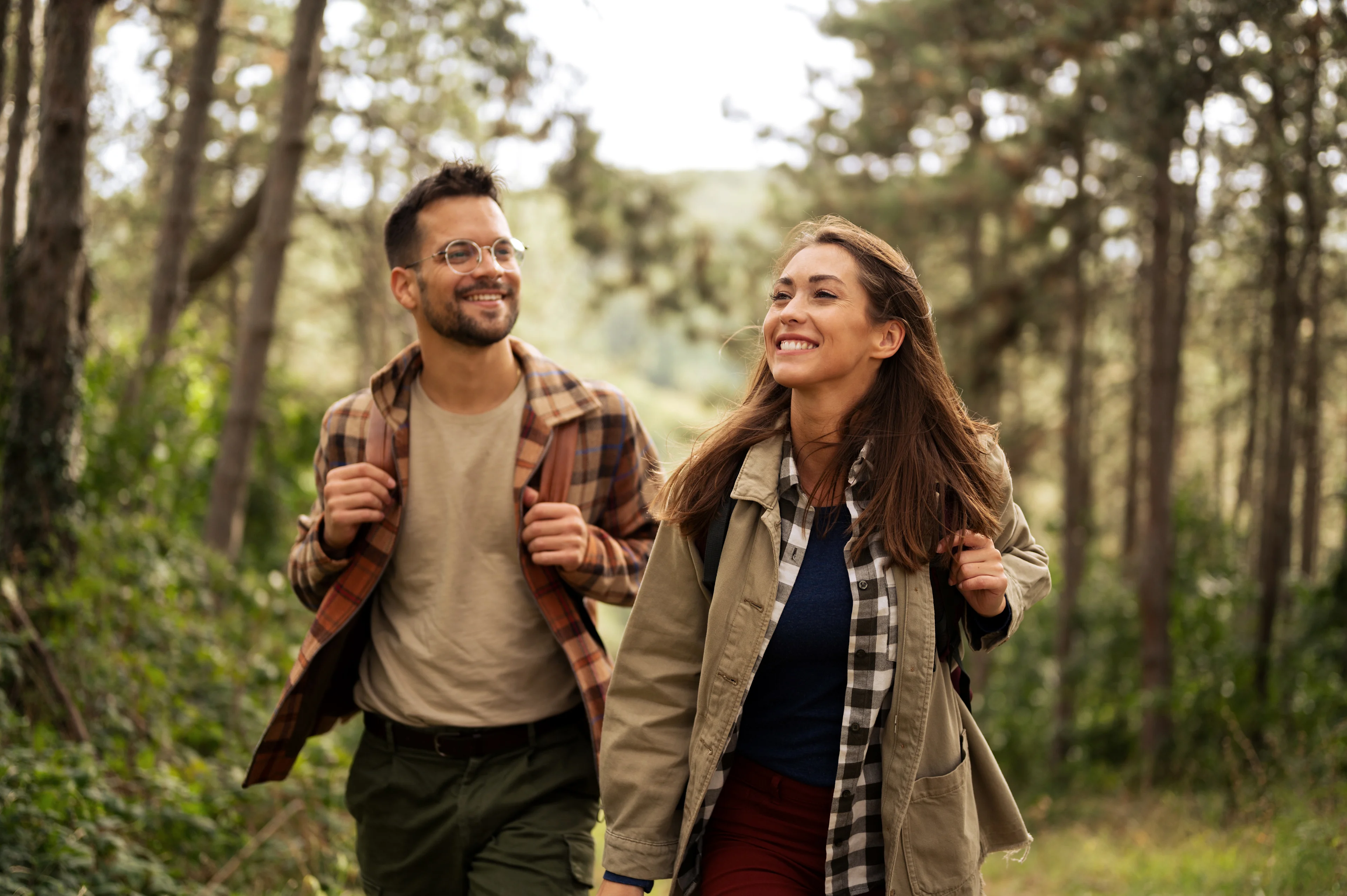Mies ja nainen ulkoilevat rennosti vehreässä metsässä