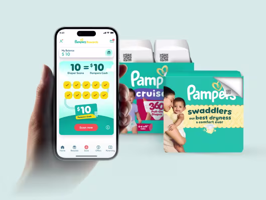 Hand holding a phone showing the Pampers rewards app homescreen