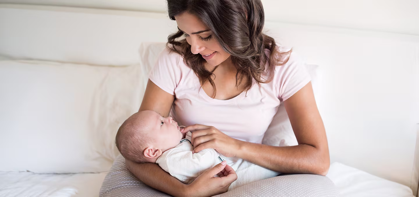 Smiling mother gently cradling her baby in a cozy setting.