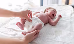 A premature baby lying on their back wearing a preemie diaper