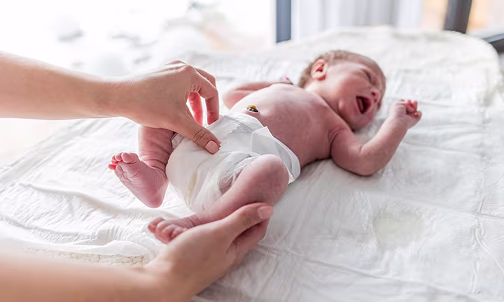 A premature baby lying on their back wearing a preemie diaper