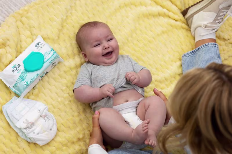 Mom sitting on the floor looking down at her smiling baby