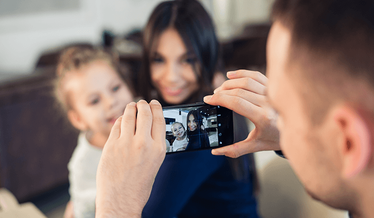 Father taking picture of two kids on smartphone