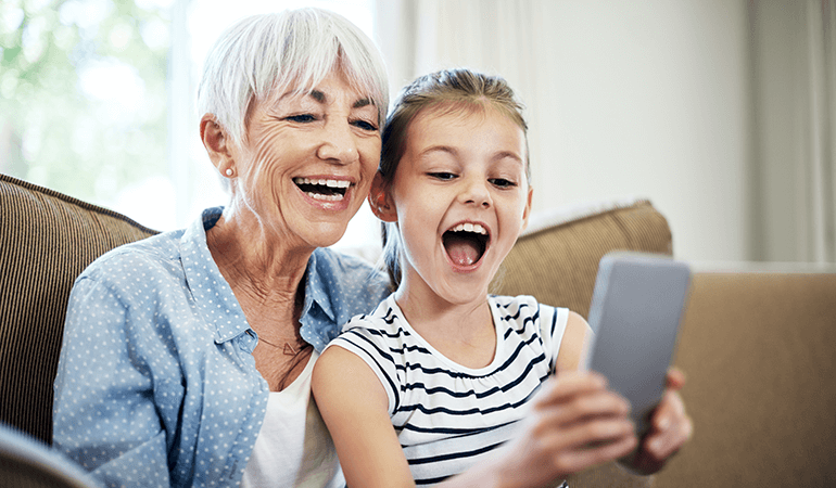 Happy grandmother and grand daughter using a smartphone