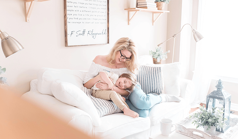 Mother cuddling with young daughter on couch