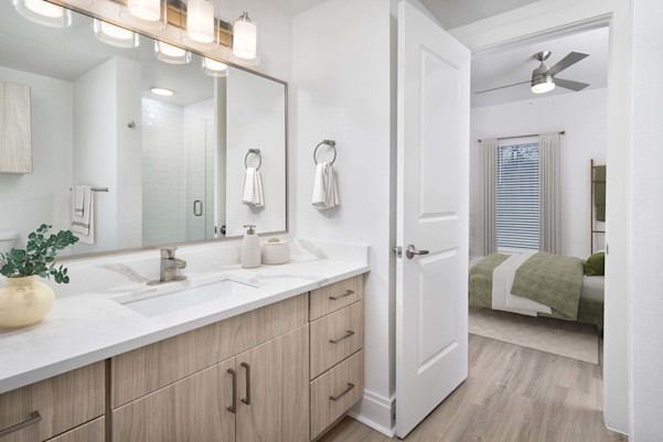 Townhome first-floor secondary bathroom with glass-enclosed shower, white quartz countertops and light wood cabinets at Camden Belmont apartments in Dallas, TX
