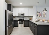 Kitchen with quartz countertops, stainless steel appliances, white upper cabinets and gray lower cabinets at Camden Heights Apartments in Houston, TX