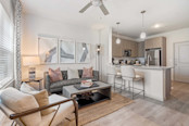 First-floor living room and kitchen with wood-style floors and extended kitchen counter at Camden Leander apartments in Leander, Tx