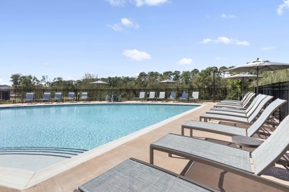 Community pool with lounge chairs at Camden Woodmill Creek in Spring, TX