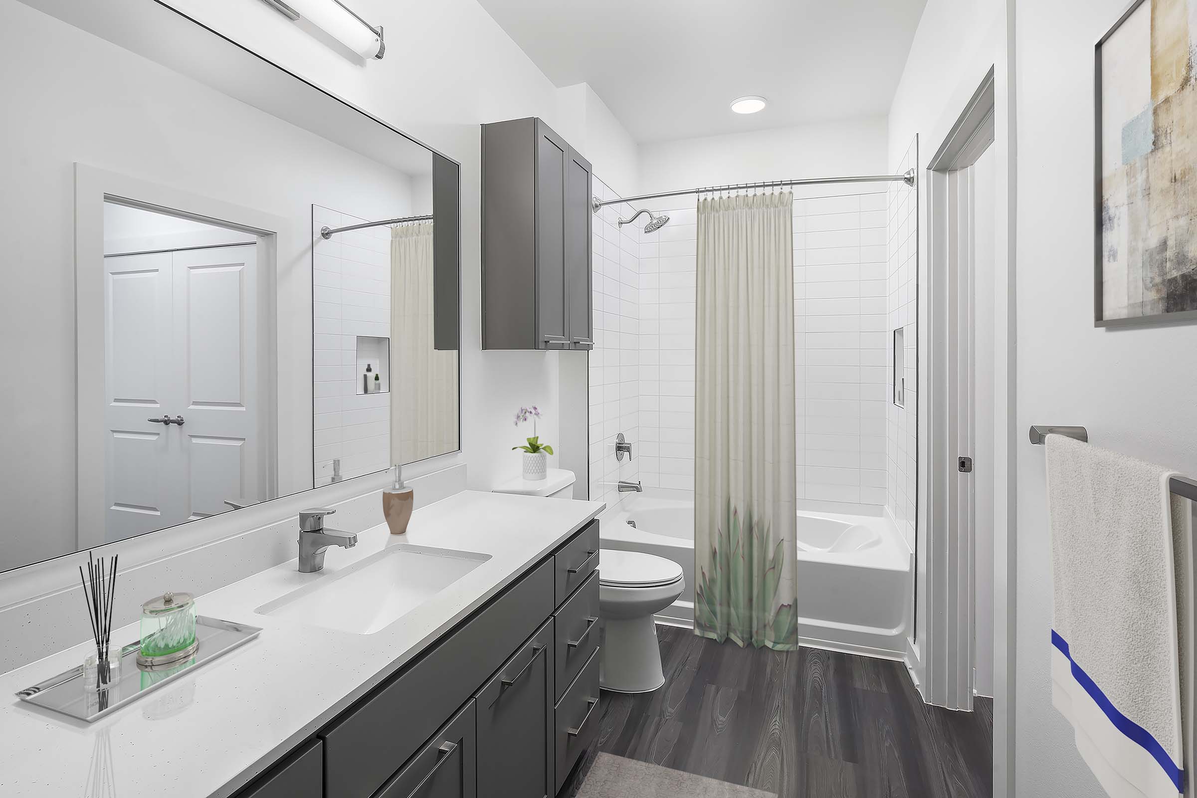 Camden Tempe West Apartments Tempe Arizona contemporary bathroom with gray cabinets, white shaker cabinets wood-like flooring and plenty of storage and curved shower rods