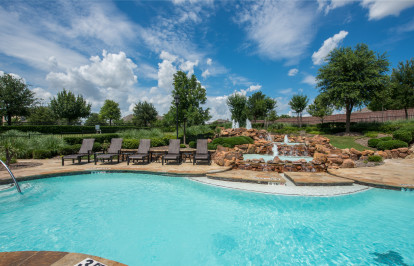 Resort-style pool with poolside deck chairs and fountains at Camden Panther Creek in Frisco, TX