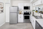 Eat in kitchen with stainless steel appliances track lighting wood look flooring and pantry at Camden Portofino apartments in Pembroke Pines, FL