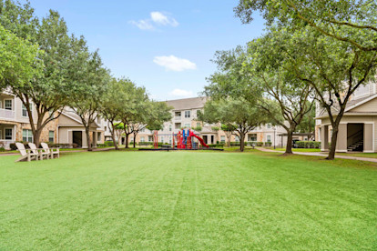 Playground and turf area with seating at Camden Downs at Cinco Ranch Apartments in Katy, TX 