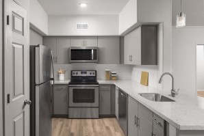 Spacious kitchen with stainless steel appliances, white quartz countertops, white subway tile backsplash, brushed nickel fixtures, and wood-like flooring