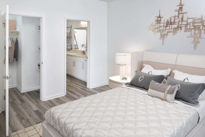 Beautifully renovated bedroom with walk-in closet featuring wood shelves and rods. The bathroom features quartz countertops, curved shower rod, rain shower head, satin nickel fixtures and hardware, and LED vanity lighting.